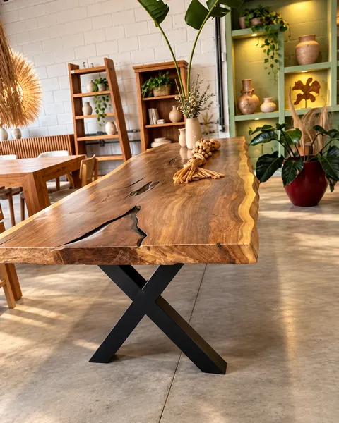 Mesa de prancha natural com base em X preta em ambiente com plantas