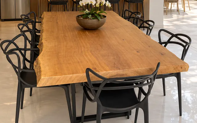 Mesa de prancha natural em área gourmet com cadeiras pretas e orquídeas (imagem ilustrativa)