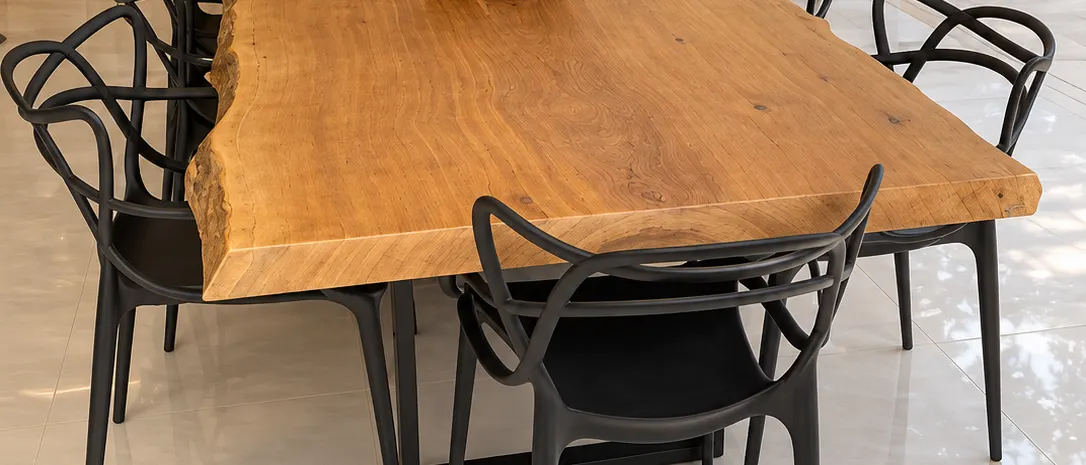 Mesa de prancha natural em área gourmet com cadeiras pretas e orquídeas (imagem ilustrativa)