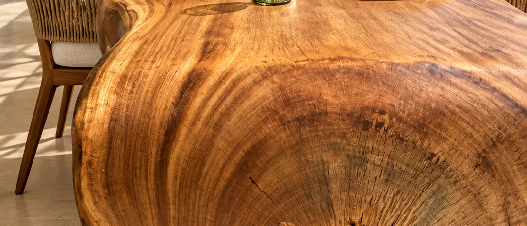 Mesa de madeira maciça posta para jantar, com ponta em cascata mostrando os anéis do tronco (imagem ilustrativa)