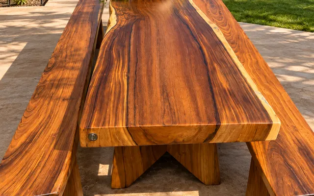 Mesa de prancha com bancos de madeira em terraço com jardim tropical (imagem ilustrativa)